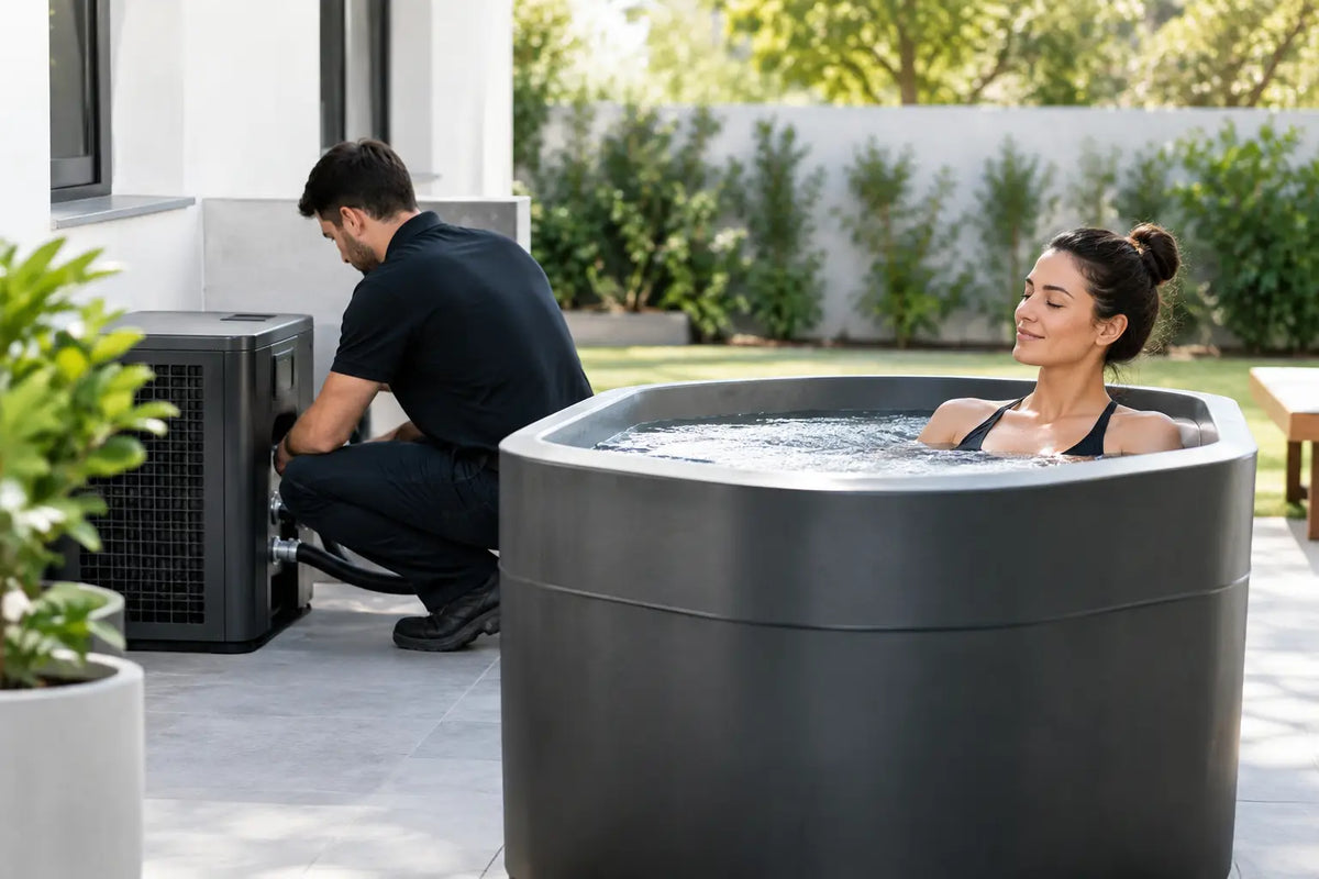 Technician connecting a chiller unit beside a cold plunge tub on a home patio while a woman relaxes in the water